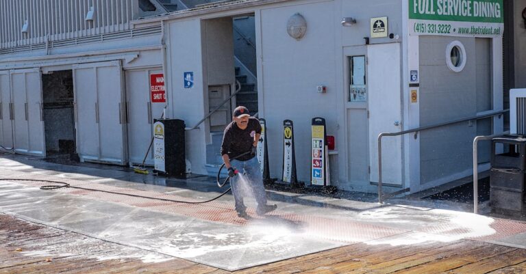 Man Cleaning Sidewalk with Garden Hose